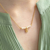Model wears pearl bar and initial charm necklace with the initial B