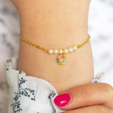 Model wears gold pearl bar bracelet with the rainbow initial  C