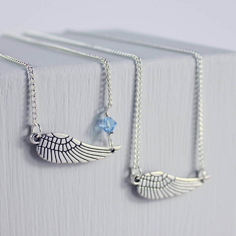 Image shows model two personalised angel wing necklace with one with December birthstone