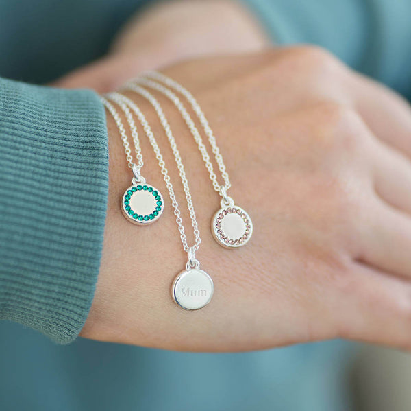 Image shows model holding three personalised birthstone disc pendant necklaces