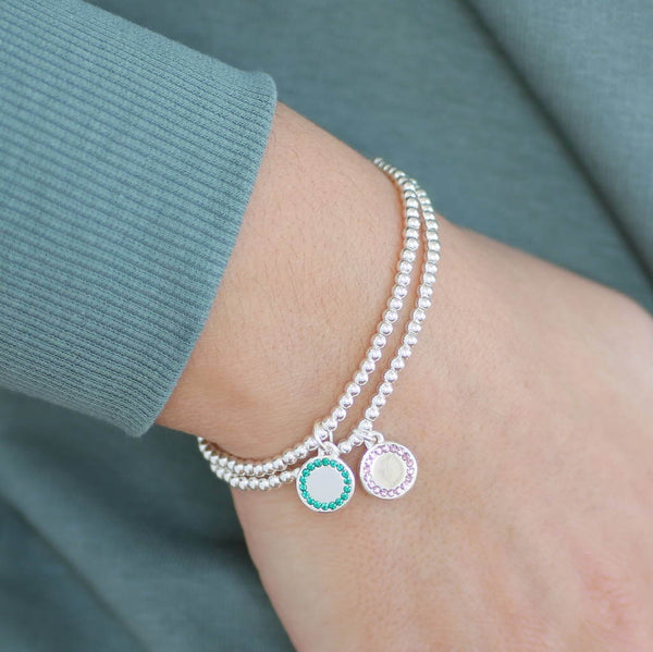 Image shows model wearing two personalised birthstone stretch bracelets on with December birthstone and the other June
