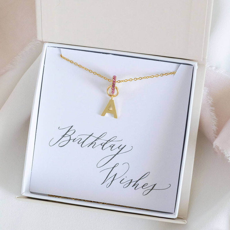 Images shows  personalised birthstone ring initial necklace with the initial A and October birthstone ring in a gift box on a birthday wishes sentiment card