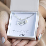 Model holds gift box with personalised bridesmaid charm bracelet  in it on a wear it with JOY sentiment card