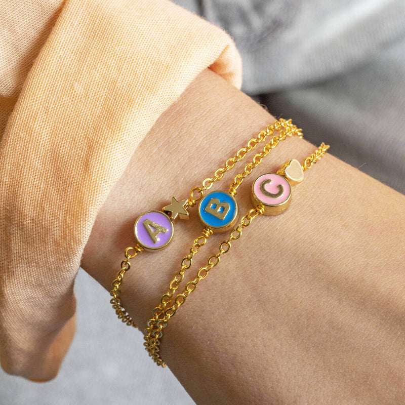 Image shows model wearing three Personalised Enamel Disc Initial Bracelet with the initial A,Band C