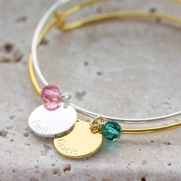 Image shows two personalised engraved disc birthstone bangles the silver withe the nameEmily and October birthstone and the gold with the name Gracie and December birthstone