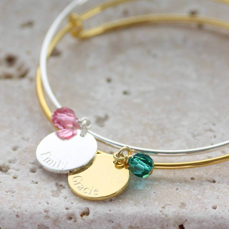Image shows two personalised engraved disc birthstone bangles the silver withe the nameEmily and October birthstone and the gold with the name Gracie and December birthstone