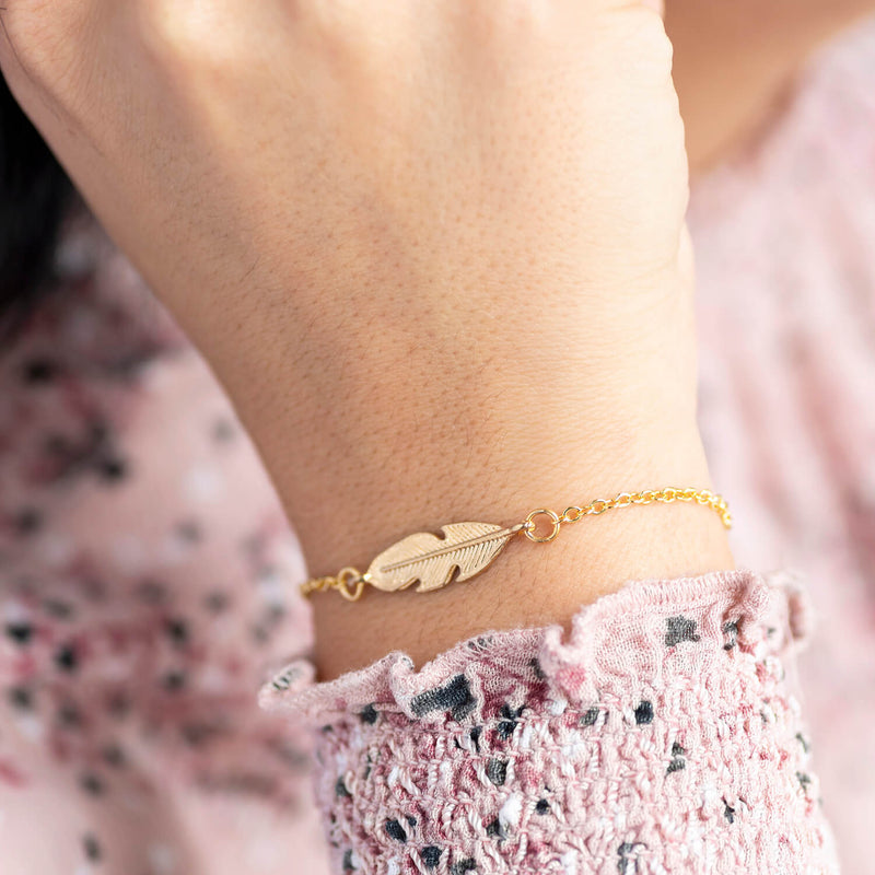 Image shows model wearingPersonalised Gold Feather Bracelet