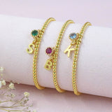 Images shows three personalised gold plated beaded birthstone bracelet on a bracelet holder