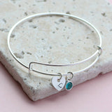 Image shows personalised heart birthstone bangle with initial L and December birthstone