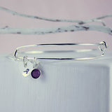 Image shows personalised heart birthstone bangle with initial A and February birthstone