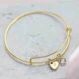 Image shows personalised heart of gold birthstone bangle with A engraved the heart and light amethyst birthstone