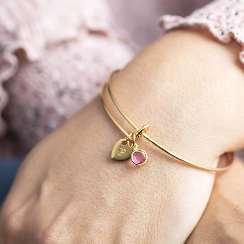 Image shows personalised heart of gold birthstone bangle with P engraved on the heart and rosebirthstone
