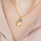 Image shows model wearing personalised heart of gold birthstone necklace with the letter C engraved the heart and December birthstone