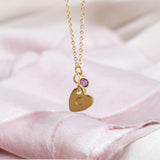 mage shows hanging personalised heart of gold birthstone necklace with the letter C engraved the heart and February birthstone