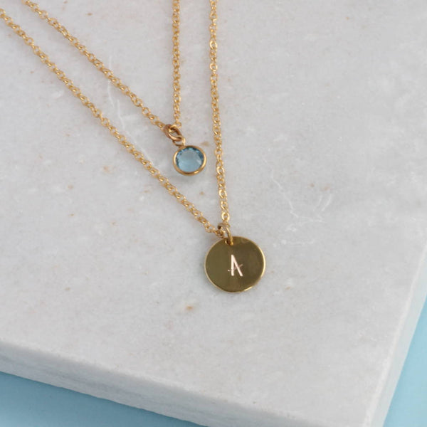 Image shows personalised layered birthstone necklace with March birthstone and Initial disc with A on it