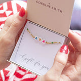 Image shows model holding personalised name enamel chain bracelet with the name Ava in a gift box on A gift for you sentiment card