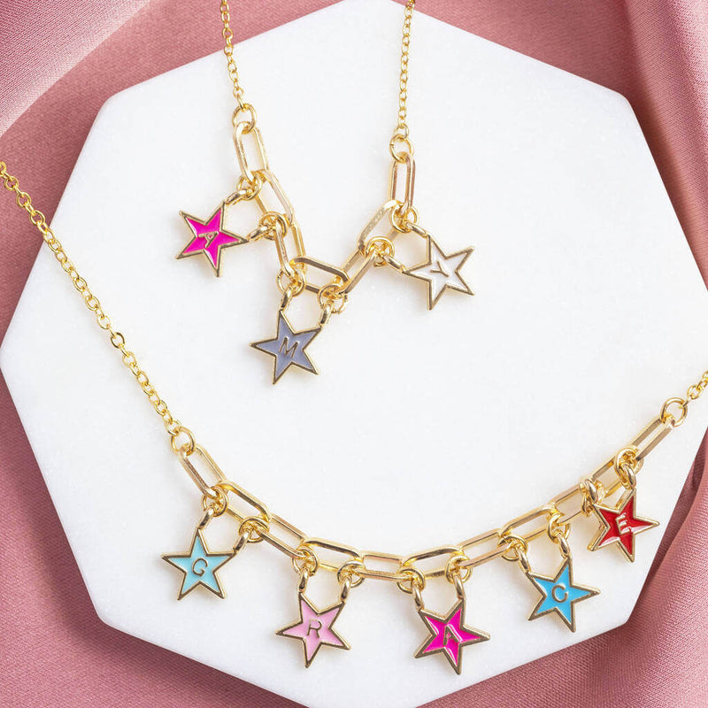  Image shows two personalised name in stars enamel necklaces one with the name AMY and theatre with GRACE