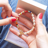 Model holds personalised pearl and seed bead bracelet with the initial K and gift box underneath 