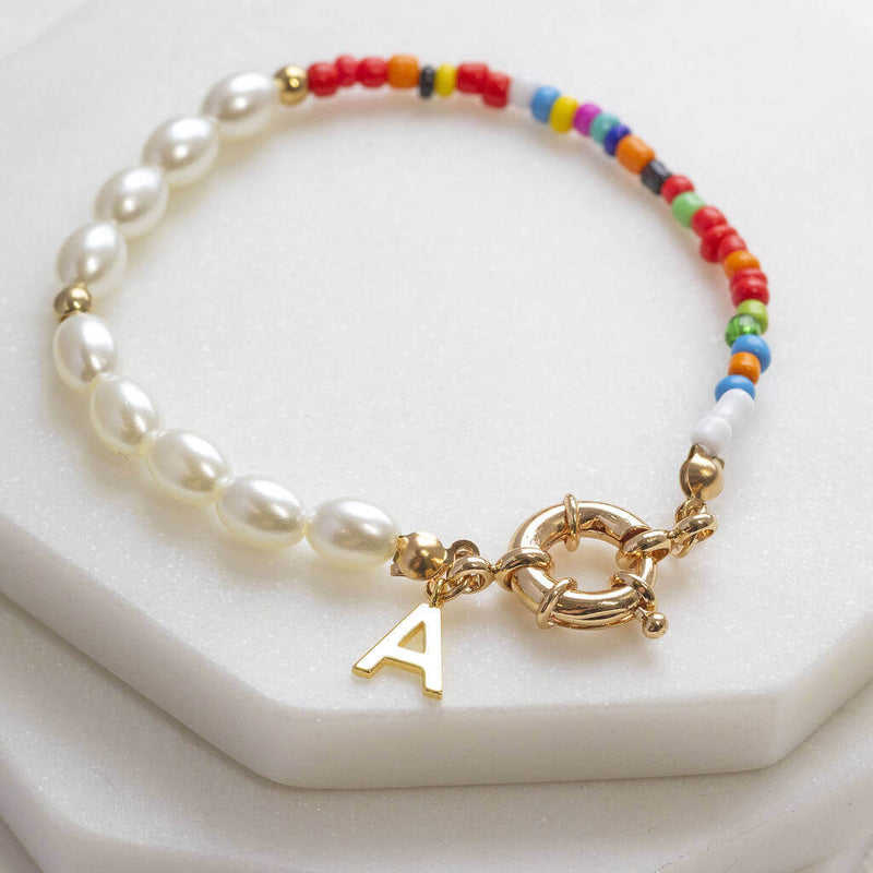 Personalised pearl and seed bead bracelets with the initial  A sitting on top two stacked marble hexagon coasters