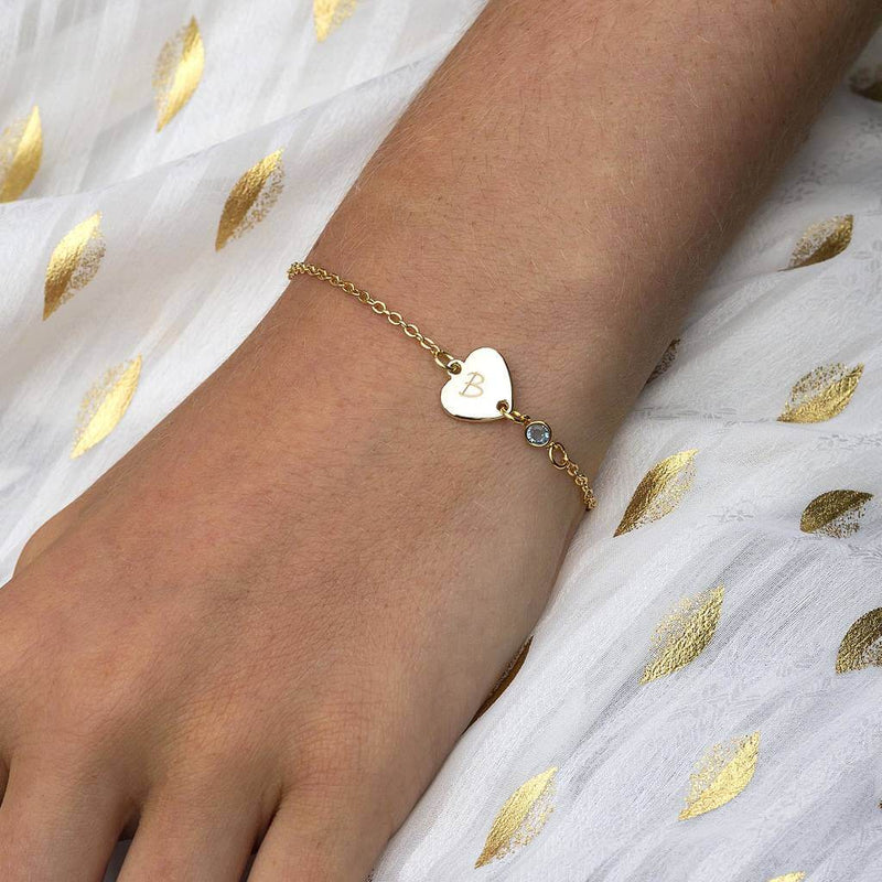 Image shows model wearing personalised sideways heart birthstone bracelet engraved with the letter B and March birthstone