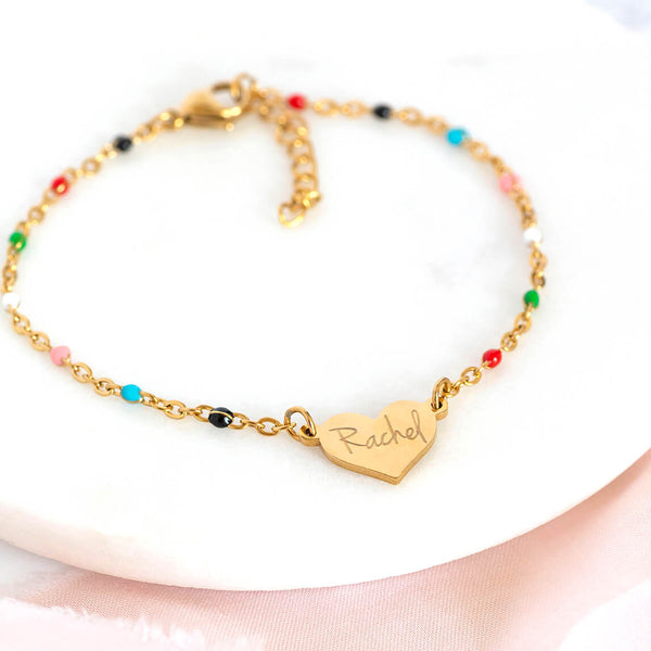 Image shows personalised rainbow enamel heart bracelet with the name Rachel