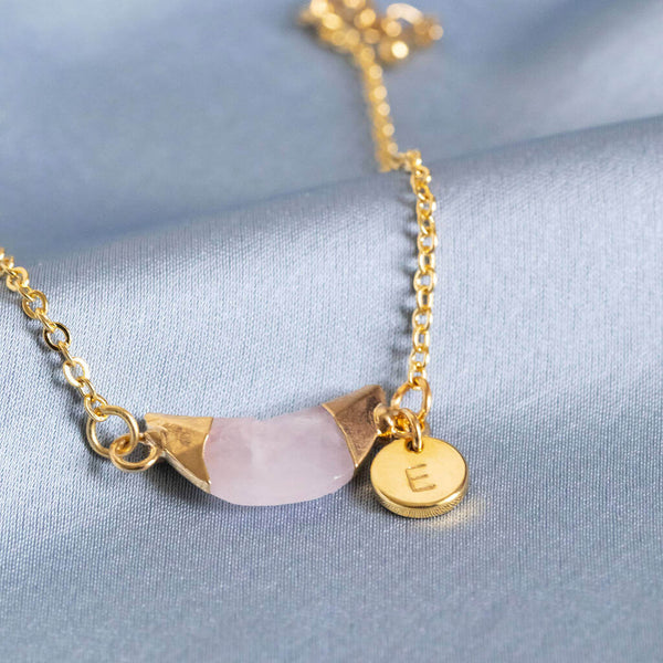 Image shows personalised rose quartz half moon bracelet with disc with the initial E on it