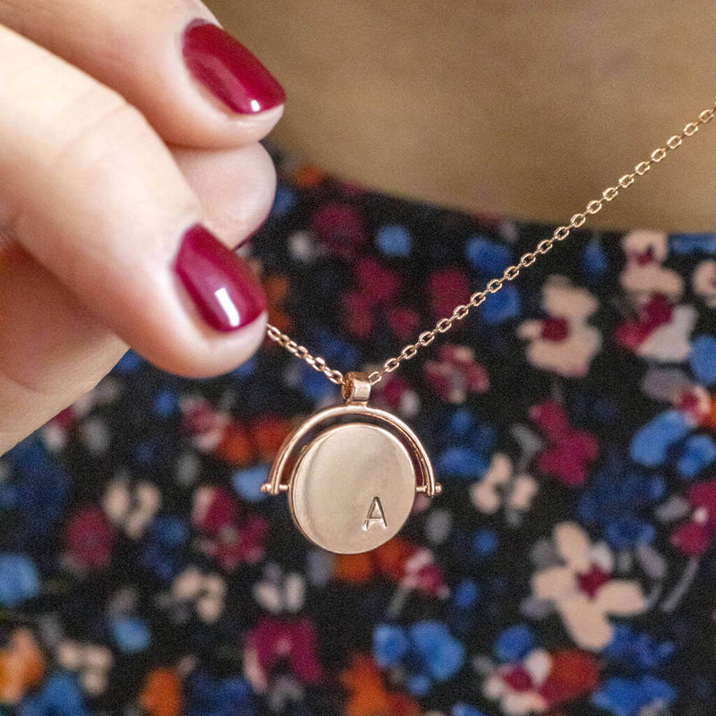 Image shows model holding rose gold personalised spinner necklace with initials A