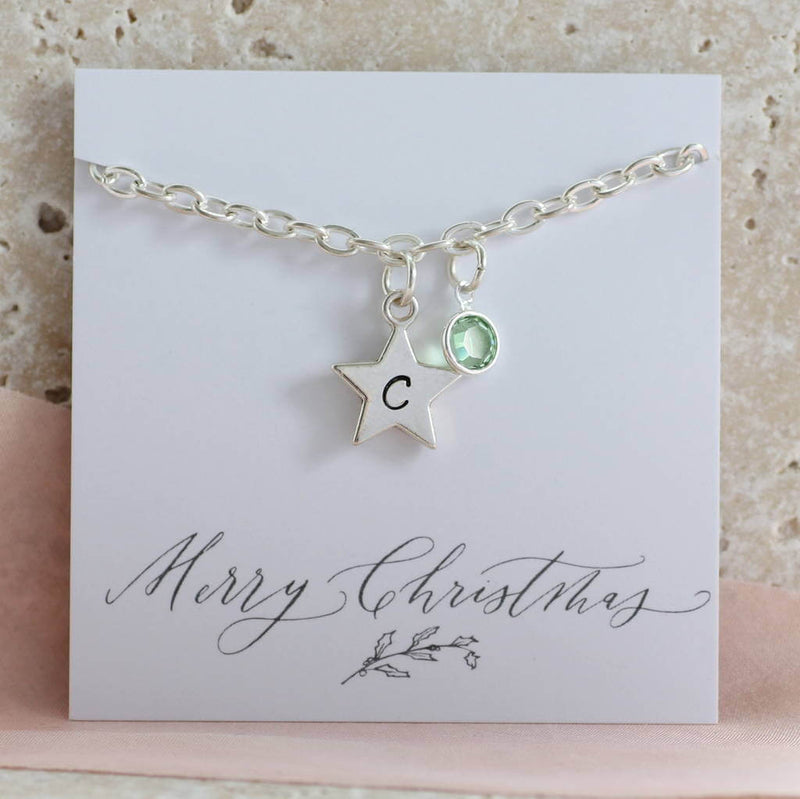 Image shows personalised star charm bracelet with a star engraved with the letter C and August birthstone on a Merry Christmas sentiment card