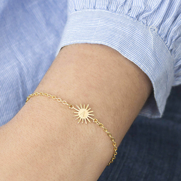 Image shows model wearing  gold personalised sunburst bracelet engraved with the initial A