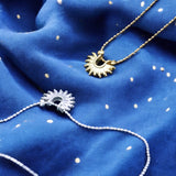 image shows two bracelets with sun design on a deep blue fabric background with scattered gold flecks