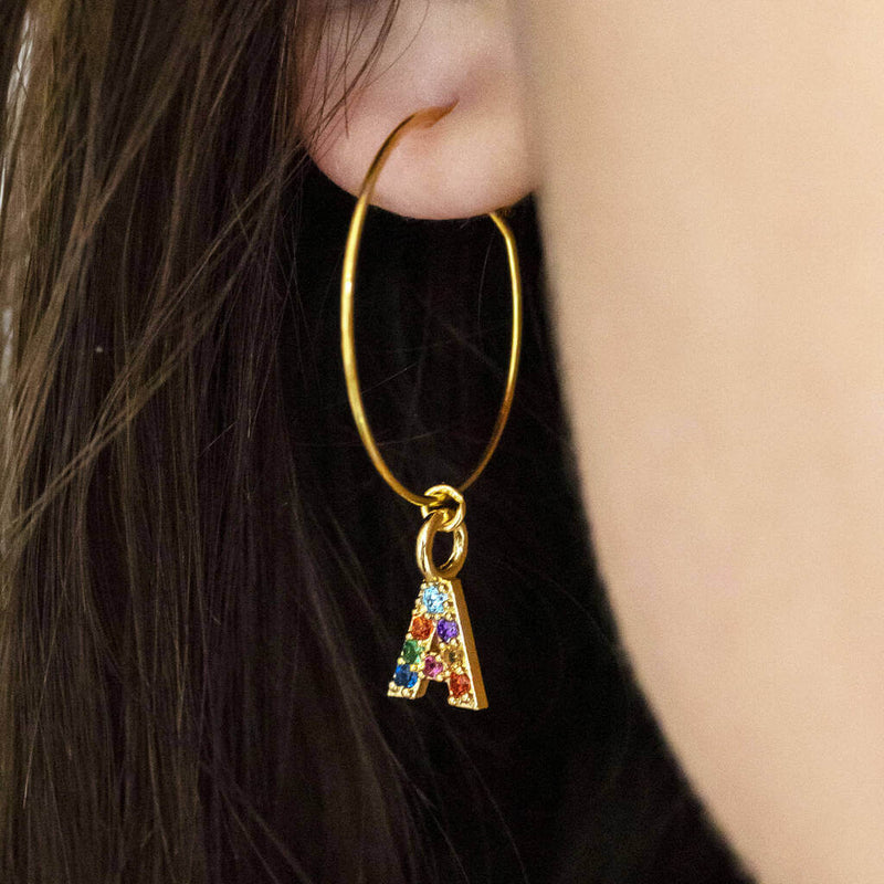 Image shows model wears rainbow initial hoop charm erring with the initial  A