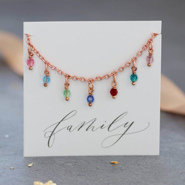 Image shows the rose gold family birthstone charm bracelet on a family sentiment card