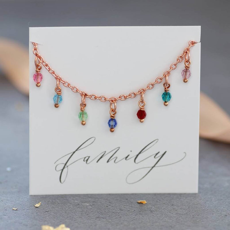 Image shows the rose gold family birthstone charm bracelet on a family sentiment card