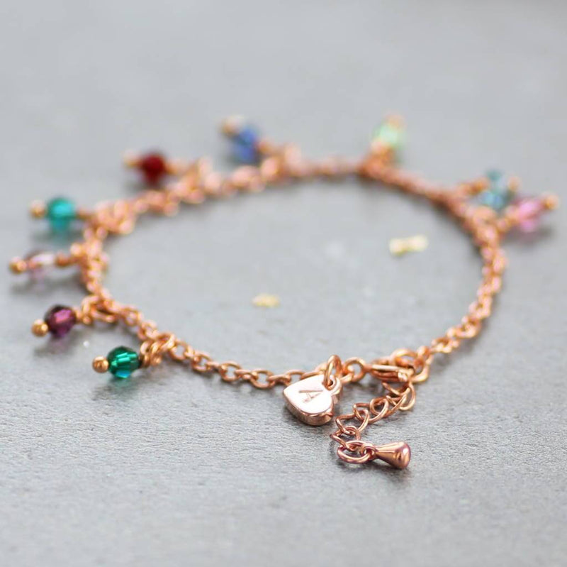 Image shows the  rose gold family birthstone charm bracelet with initial heart charm at the clasp