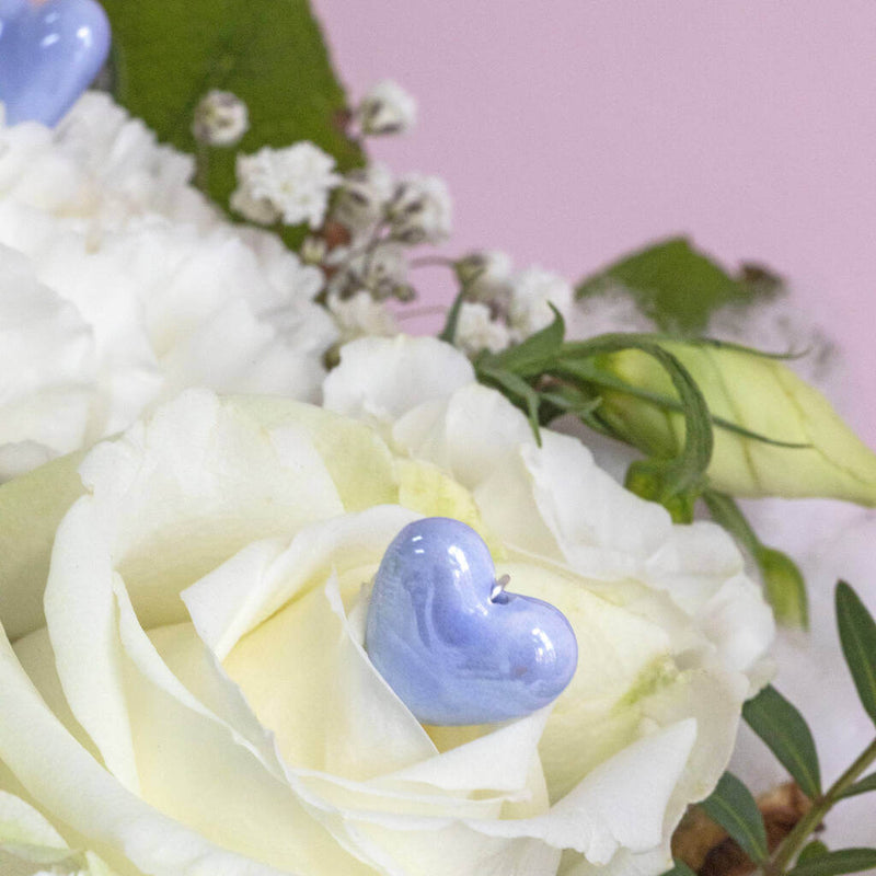 Image shows close up of something blue heart pin in ivory flowrers