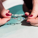 Image shows model holding Silver Friends For Eternity Birthstone Bracelet with October and September birthstone