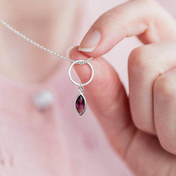 Image shows model holding Silver Circle Necklace With February Marquise Birthstone Charm