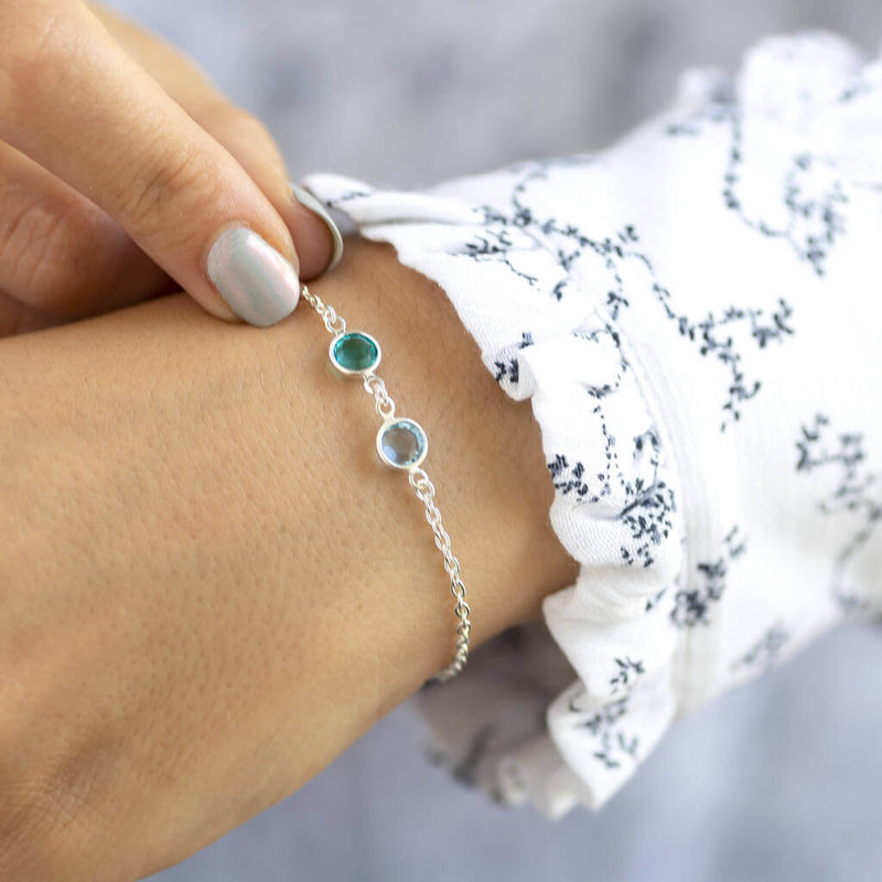 Image shows model wearing silver double birthstone bracelet with December and March birthstones