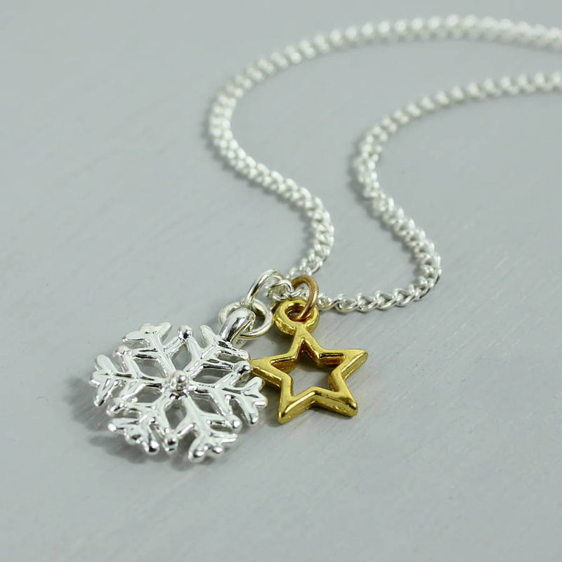 Image shows  silver snowflake birthstone charm necklace with gold star charm