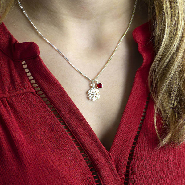 Image shows model wearing silver snowflake birthstone charm necklace with July birthstone