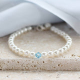 Something blue bridal bracelet with blue crystal on main bracelet sitting on a stone surface with white material the background