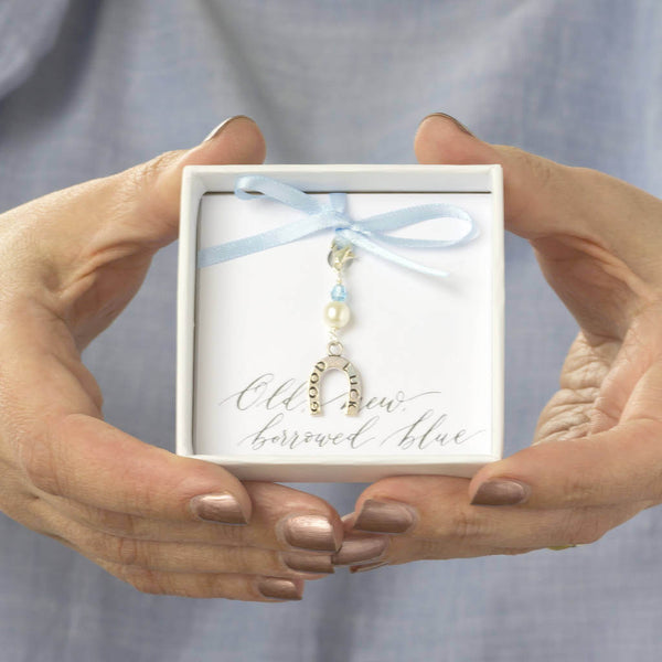 Model holds gift box with something blue lucky horseshoe charm attached to old new borrowed blue sentiment card with baby blue ribbon