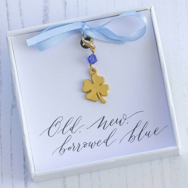 Something blue lucky four leaf clover charm in a gift box on a old new borrowed blue sentiment  card