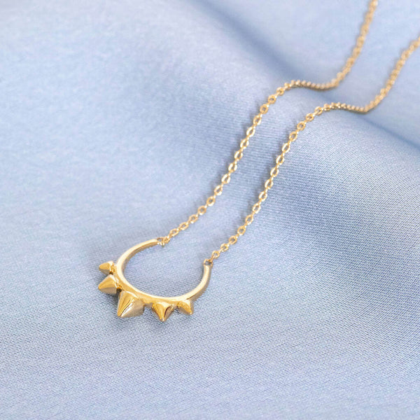 Image shows Spiked Arc Necklace on blue background