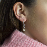 Image shows model wearing Sterling Silver Infinity Pearl Earrings