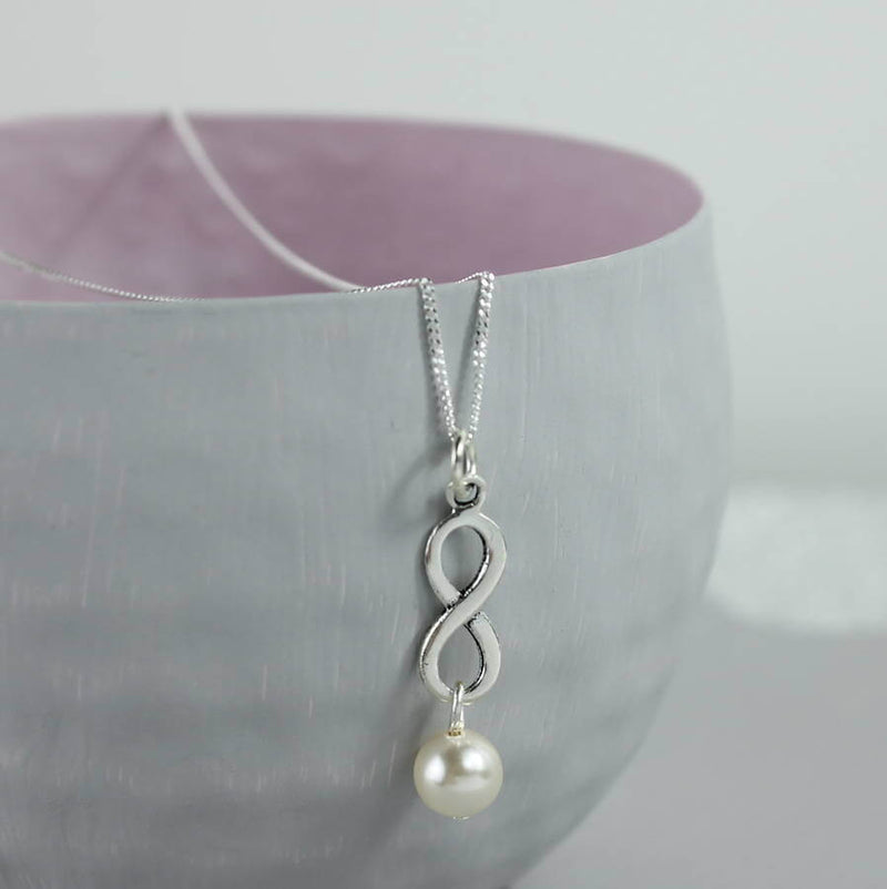 Image shows Sterling Silver Infinity Pearl Pendant Necklace hanging over a grey bowl
