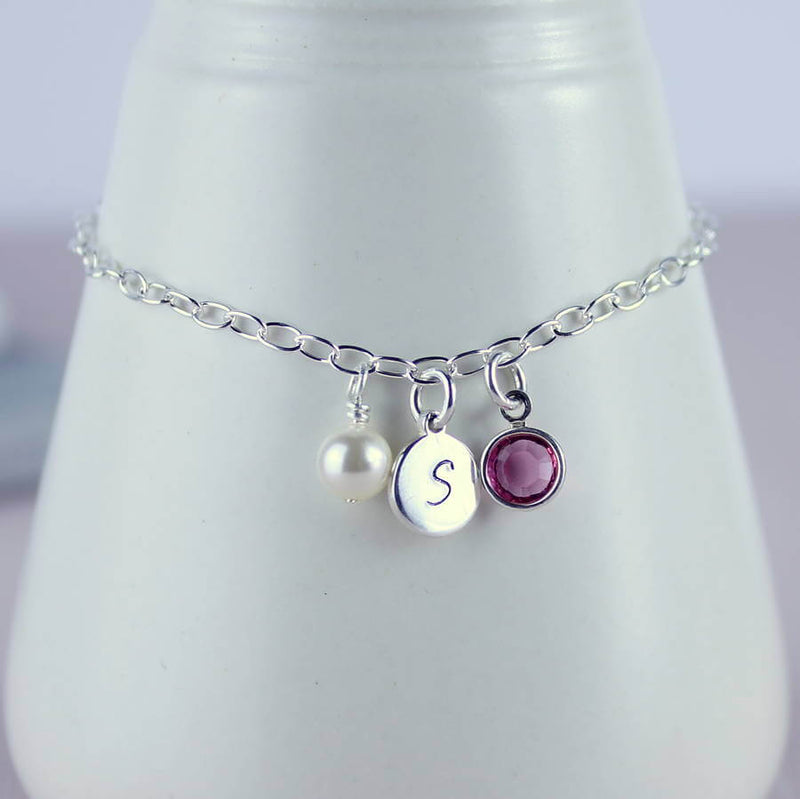 Image shows sterling silver personalised birthstone bracelet, with a pearl, Initial disc with S and February birthstone