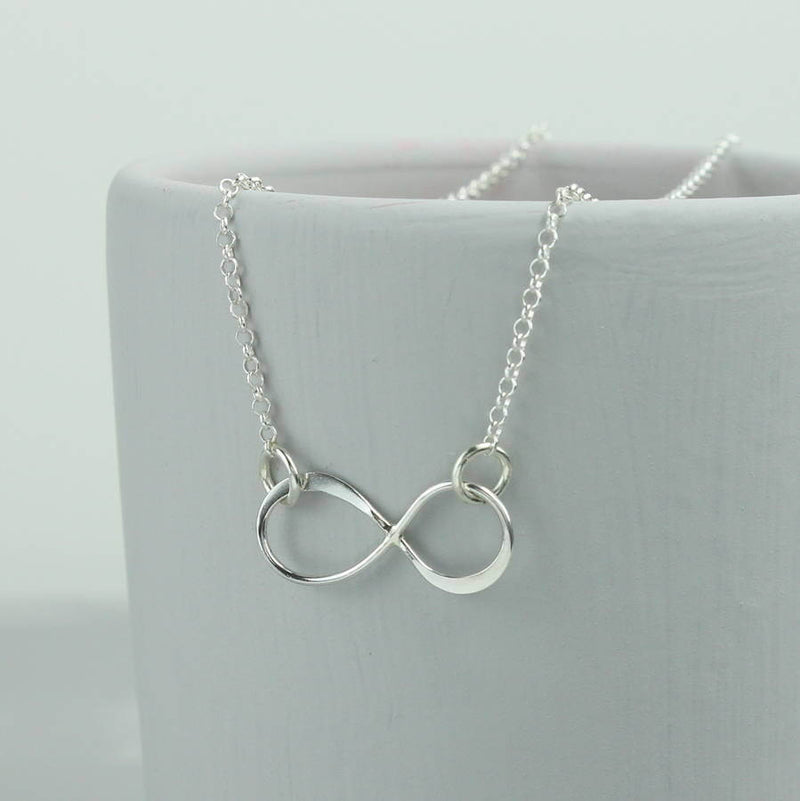 Image shows Sterling Silver Infinity Necklace hanging from a grey bowl 