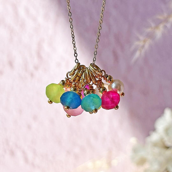Image shows Summer Essential Multiwear Bright Charm Necklace hanging against a blurred background