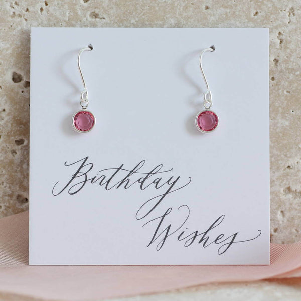 Image shows model wearing Swarovski crystal birthstone earrings with October birthstone ,on a birthday wishes  sentiment card